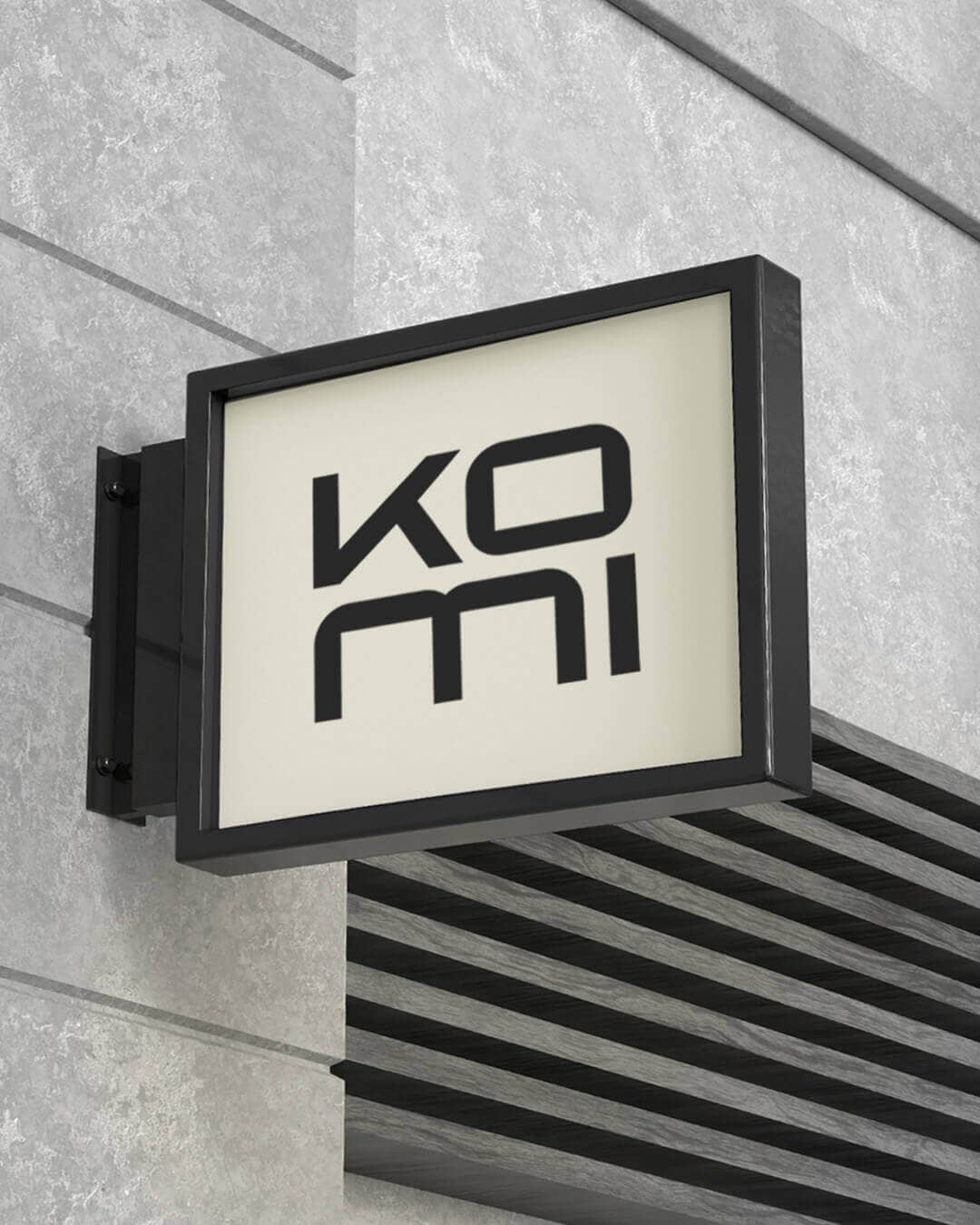 KOMI logó kültéri táblán modern építészeti környezetben építészeti studiónak